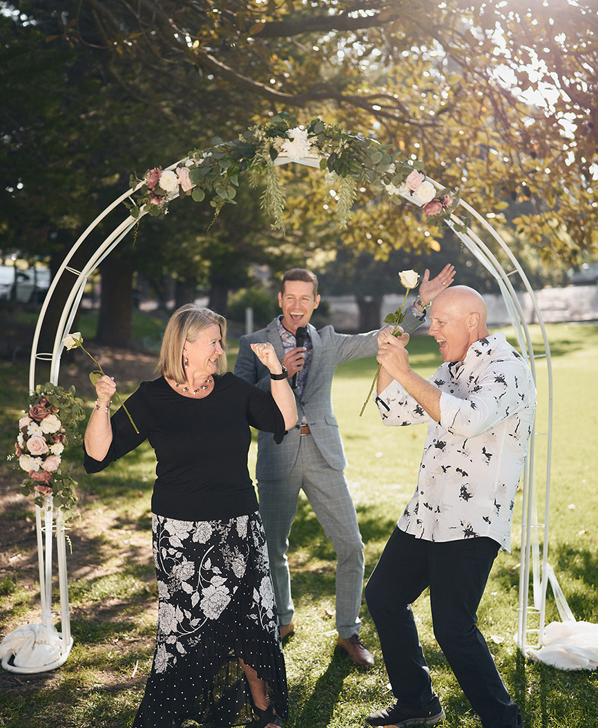 older couple celebrating under arch in nature with celebrant